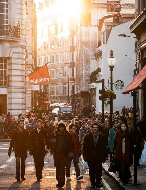 Pedestrians walking along a busy city street.